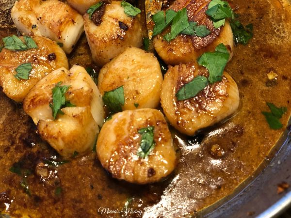 overhead shot of scallops and fresh herbs in pan 