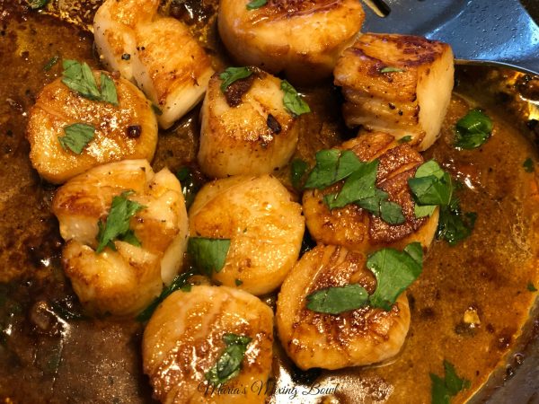 scallops in a pan with sauce and herbs on top 