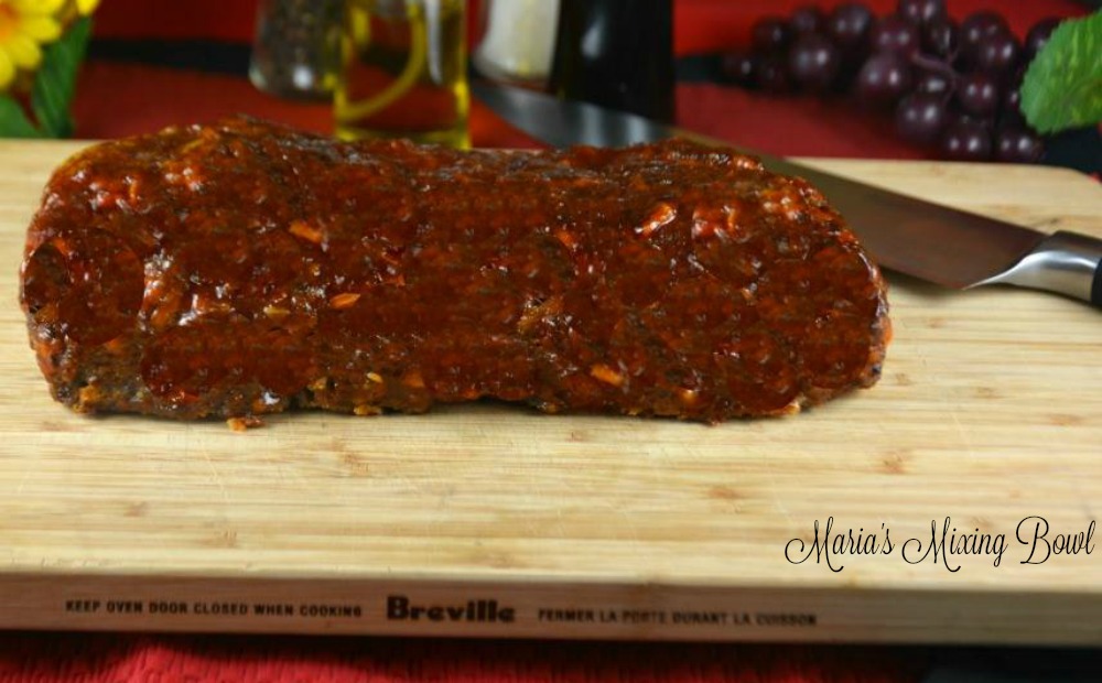 meatloaf on cutting board on red table clothe with grapes salt and pepper 