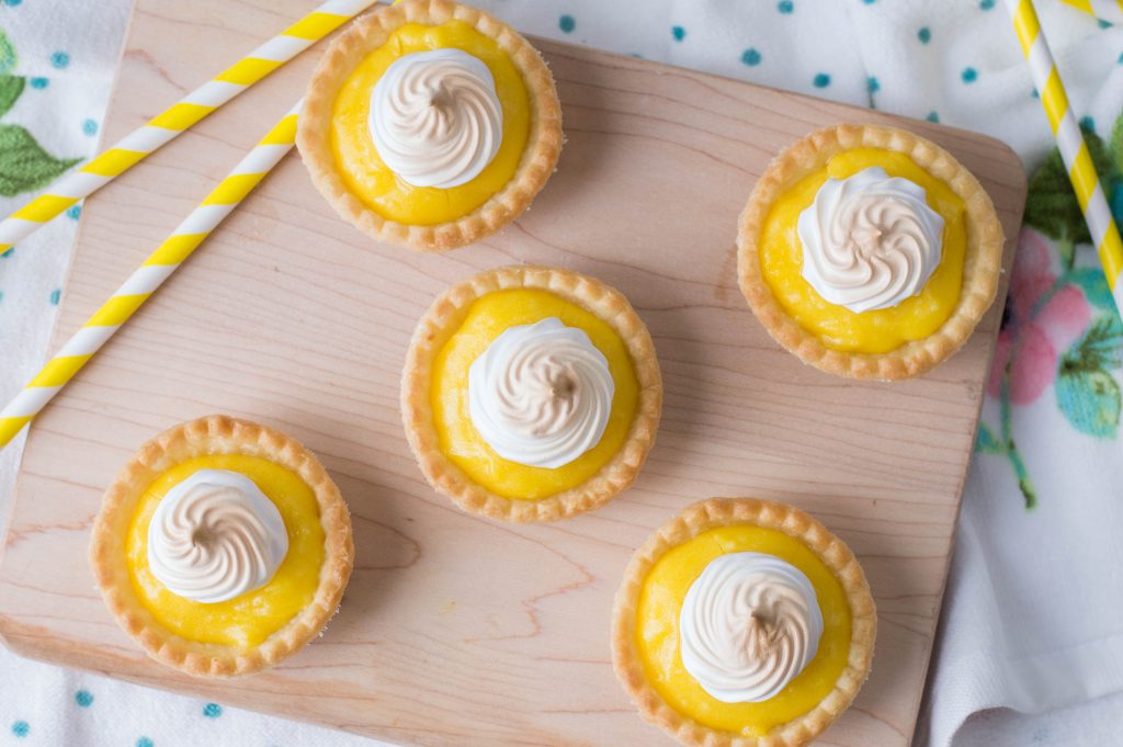 Mini pies sitting on a table with straws and a colored cloth under it