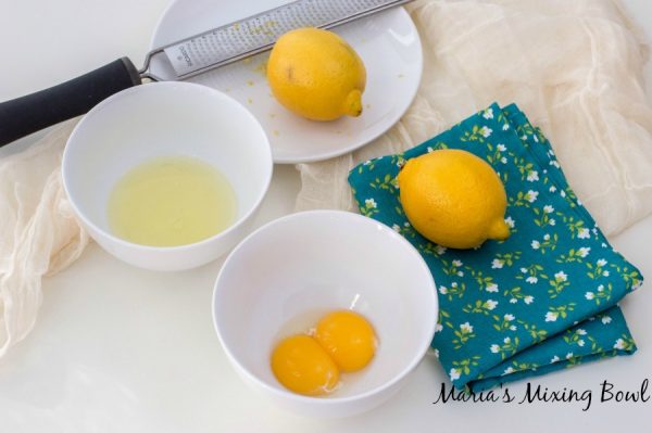egg yolks and egg whites sitting in white bowls on table with lemons and a zester beside it