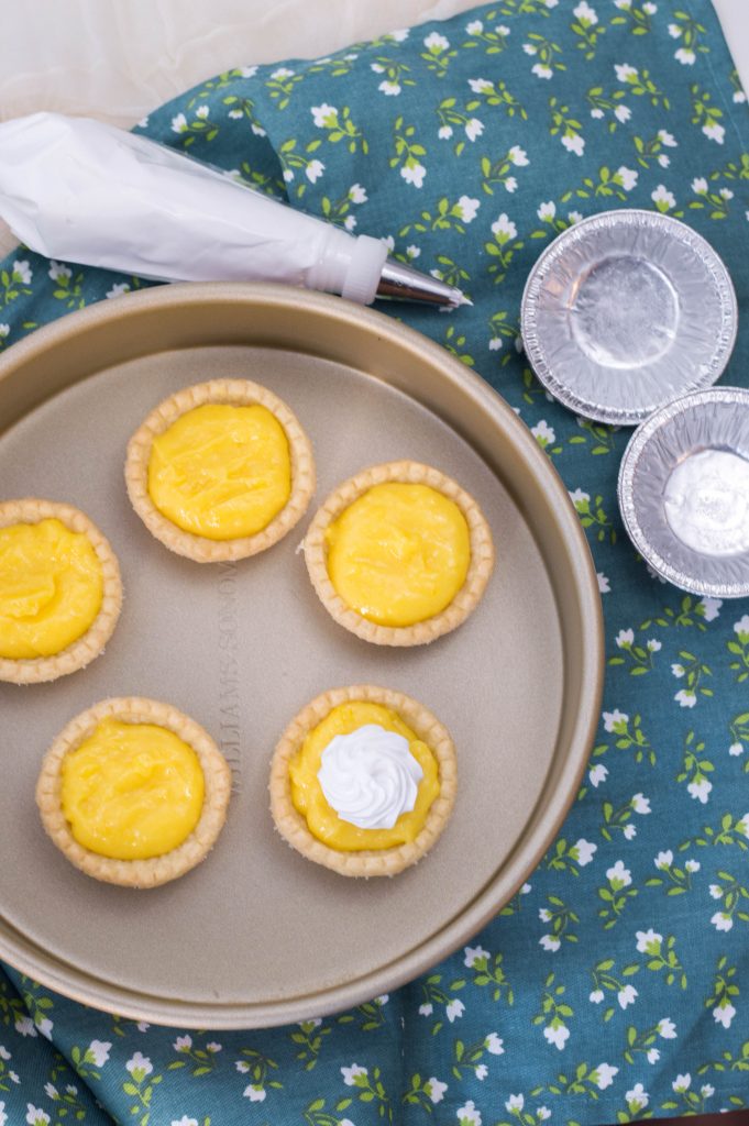 lemon custard pies with meringue on one of the mini pies sitting in the pie pan on table