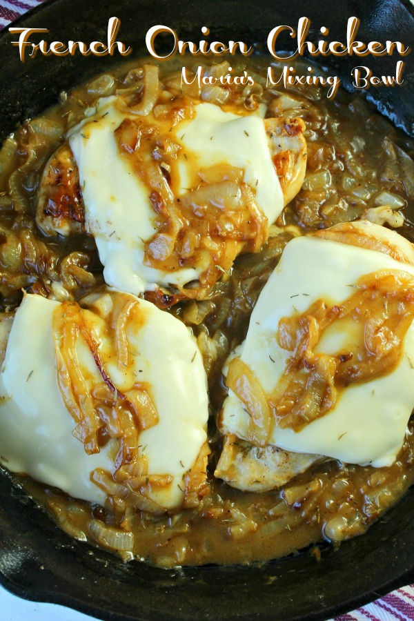 Three chicken breasts covered in melted cheese and bathed in French Onion gravy in cast iron skillet.