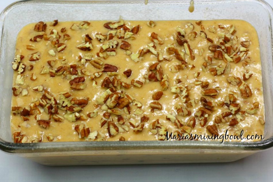 raw sweet potato bread batter in a loaf pan with nuts on top of the batter in pan 