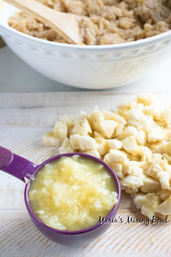 Diced bananas and a measuring cup with pineapple on a wooden table 