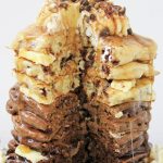A stack of ombre pancakes with chocolate chips topped with butter and chocolate chips with chok of ombre chocolate