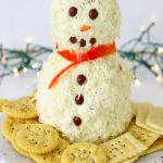 cheeseball with crackers on a white plate white lights in background