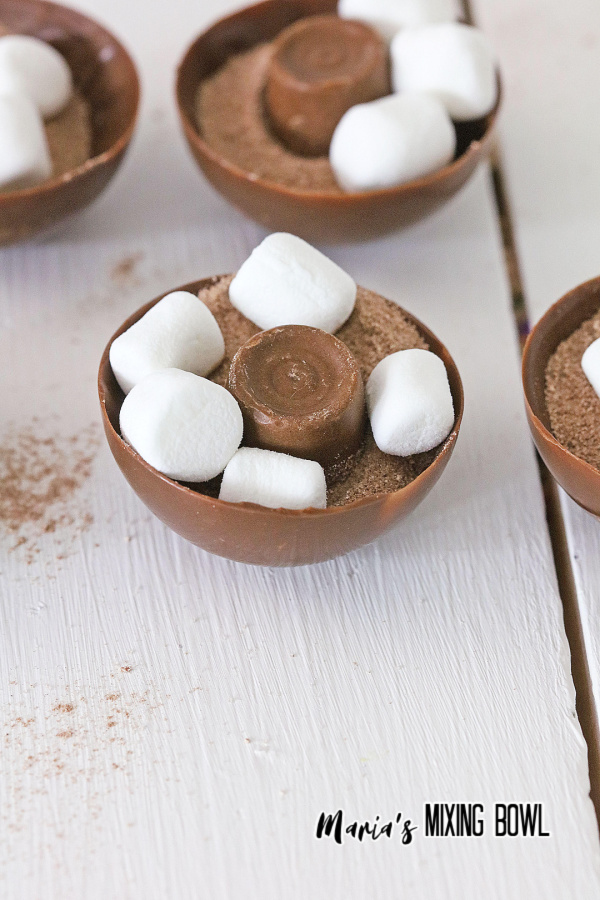 Hot cocoa bomb halves filled with ROLO'S, marshmallows, and hot cocoa mix