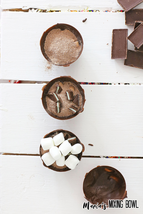 Four cocoa bomb halves showing filling process on white table
