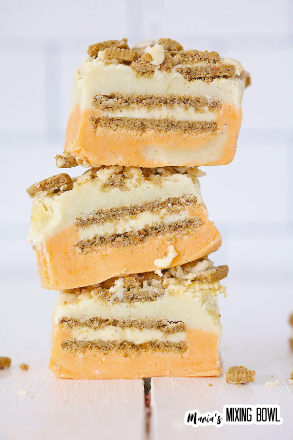 Closeup shot of three pieces of carrot cake fudge stacked atop one another.