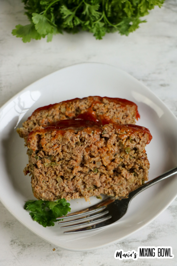 Overhead shot of two slices of meatloaf on white plate