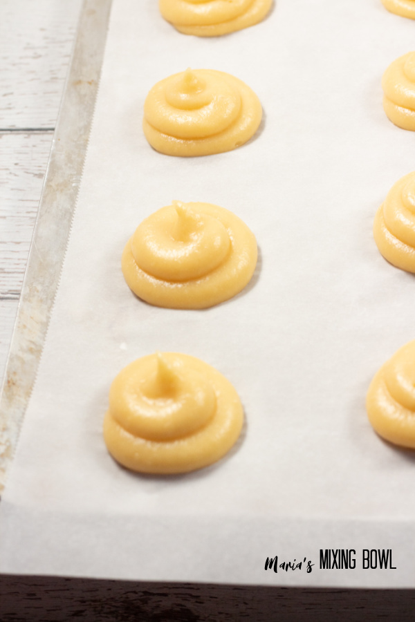 Cream puff dough on parchment paper-lined baking sheet