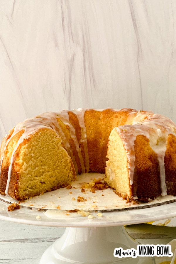 Glazed lemon lime bundt cake with a few slices removed on cake stand