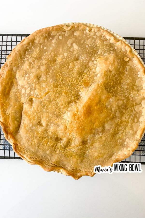 Overhead shot of cooked whole rustic chicken pot pie on wire rack