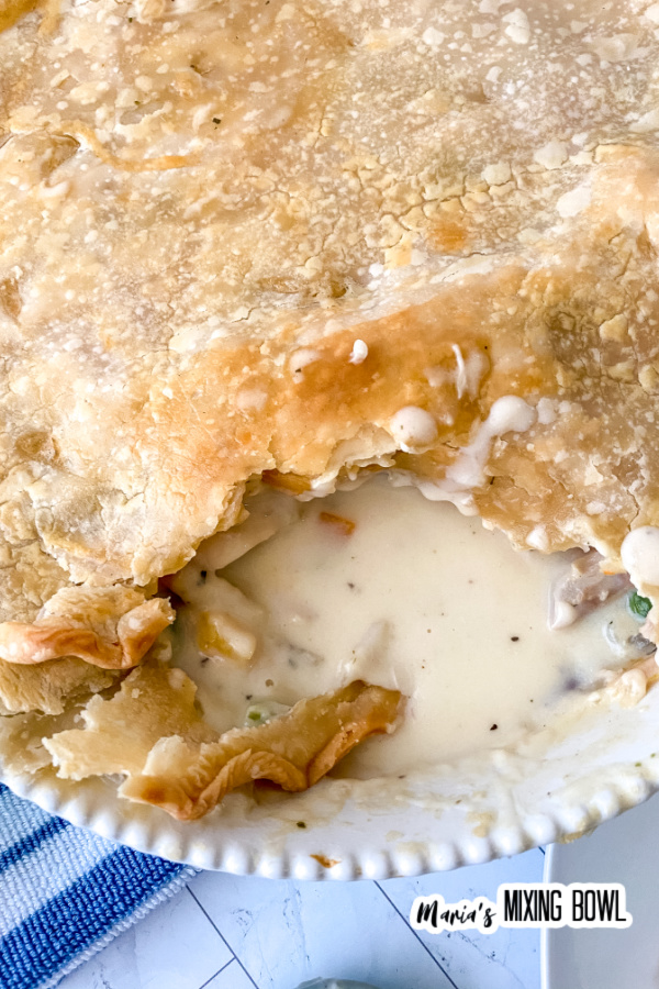 Overhead closeup shot of rustic chicken pot pie with scoop removed in pie plate