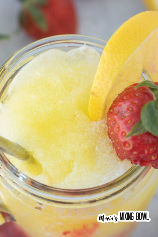 Closeup shot of frozen strawberry lemonade with strawberry and lemon garnish.