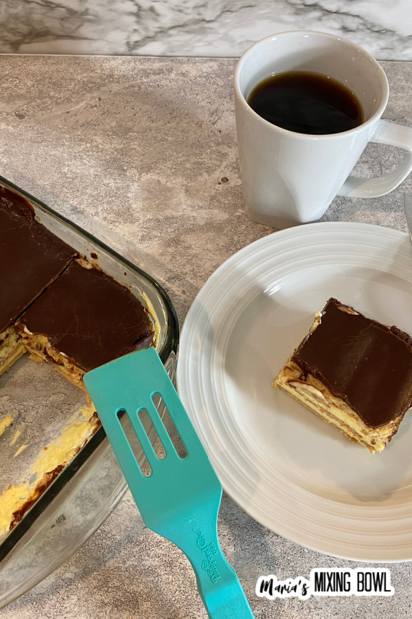 Overhead shot of chocolate eclair cake in glass baking dish next to piece of cake on white plate