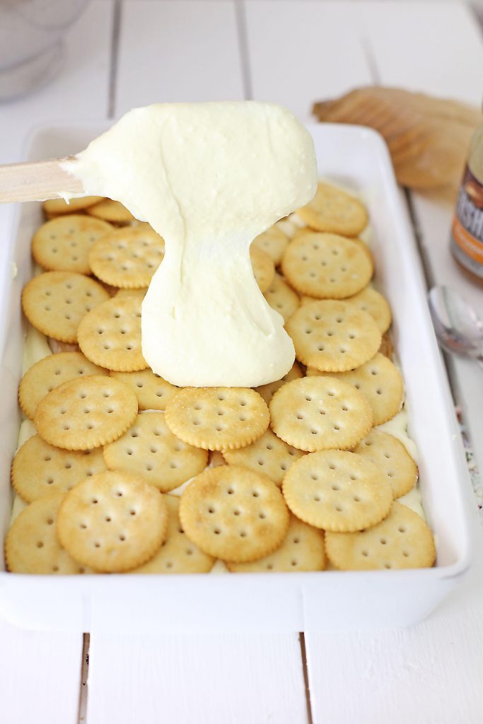 Spoon dropping cake mix over Ritz crackers.