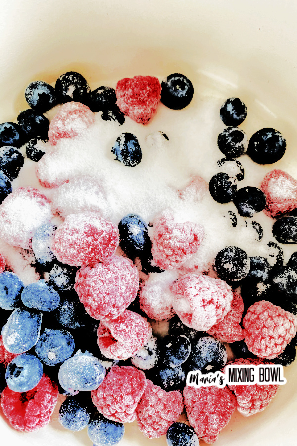 Overhead closeup shot of berries and sugar in bowl