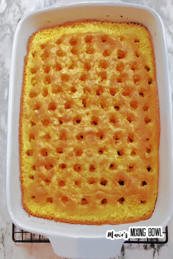 Overhead shot of cake in baking dish with holes poked in it