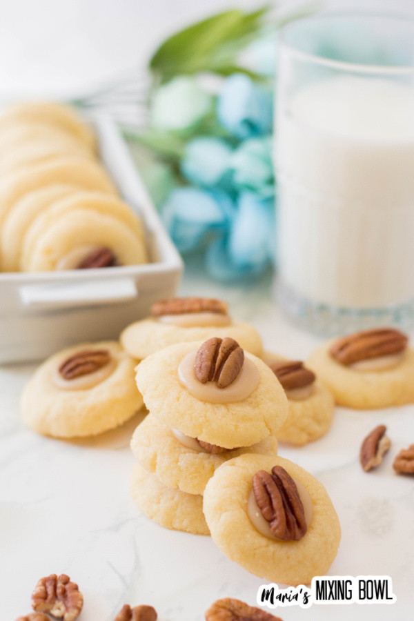 Caramel pecan thumbprint cookies in a white tray and white table