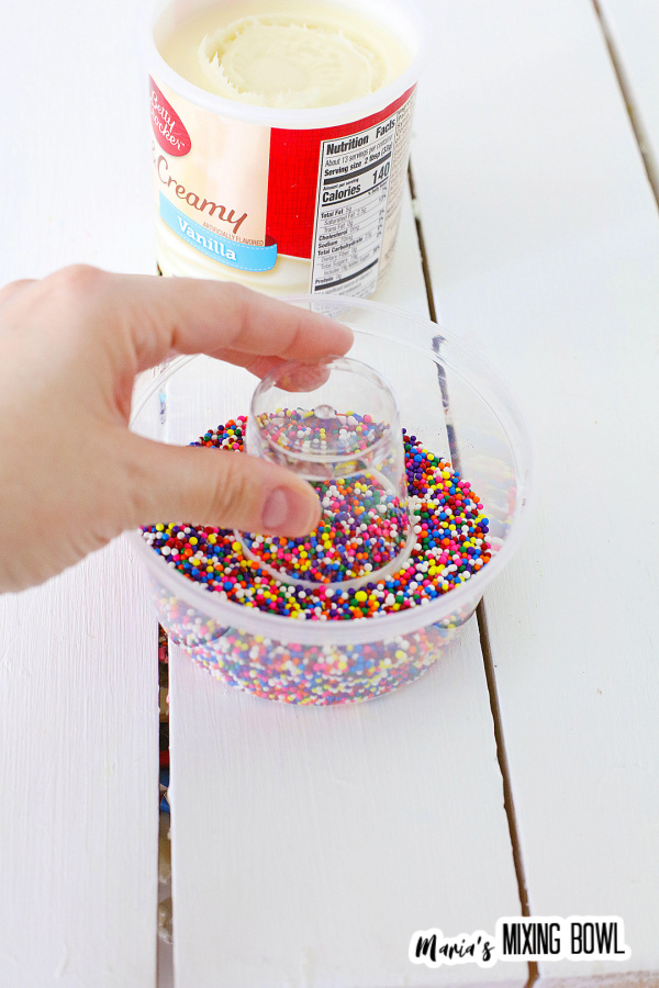 Dipping frosted glass rim into bowl of sprinkles
