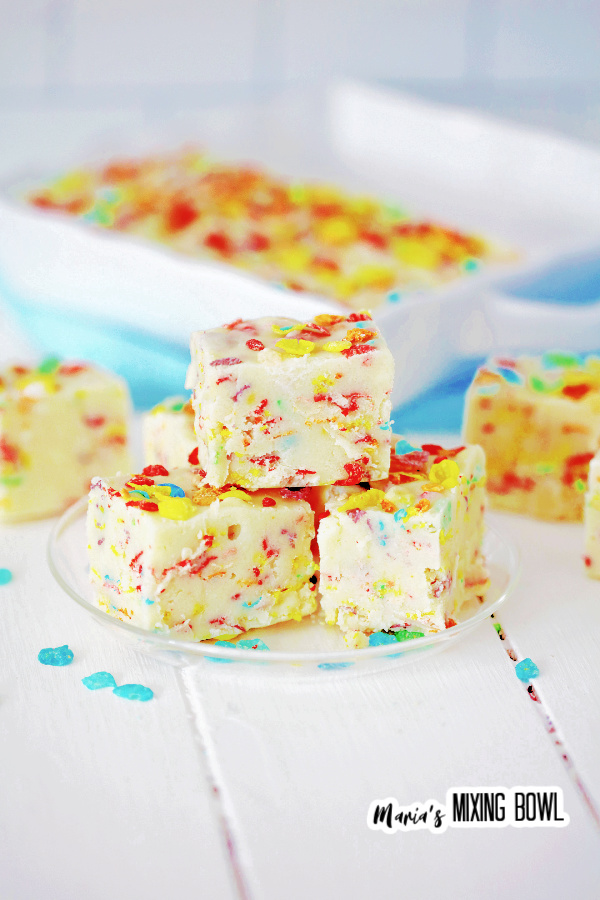 Slices of Fruity Pebbles fudge on white plate with more fudge in background
