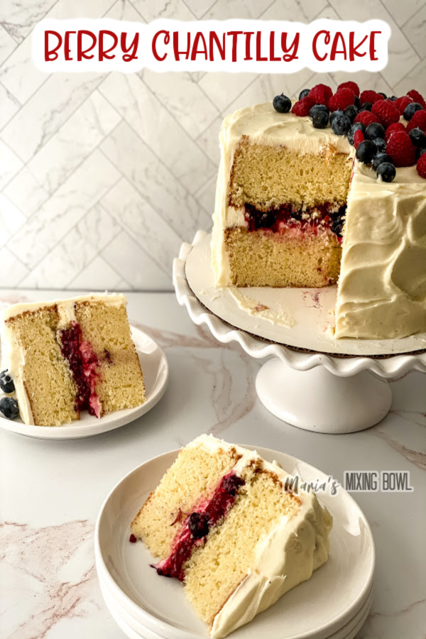Two slices of berry chantilly cake on plates with the rest of cake on cakestand