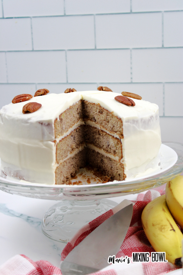 Old fashioned hummingbird cake with slice removed on cake stand.