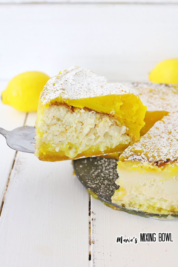 Piece of lemon bar cheesecake on spatula being removed from the whole cake