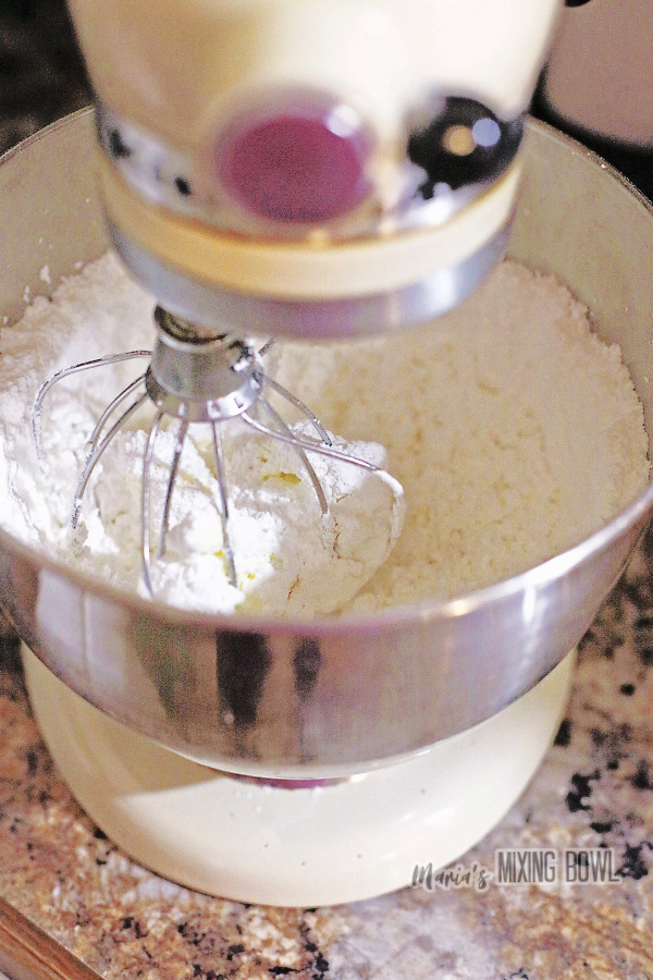 Powdered sugar being mixed into cream cheese and butter mixture with stand mixer