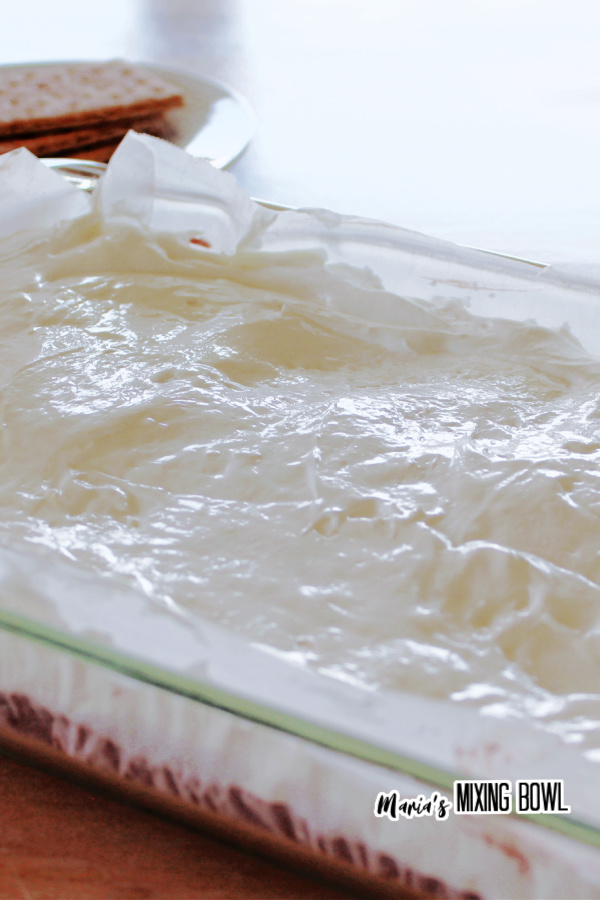 Marshmallow mixture layered over chocolate pudding in baking dish