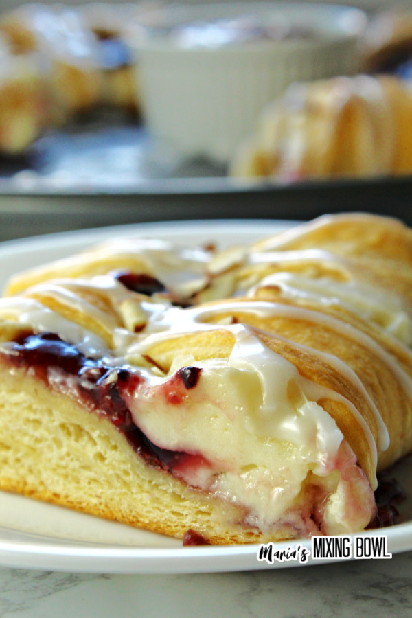 Closeup shot of slice of raspberry cream cheese crescent ring on white plate