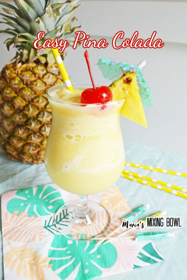 Pina Colada in a fancy glass with cherry and pineapple garnish whole pineapple in background