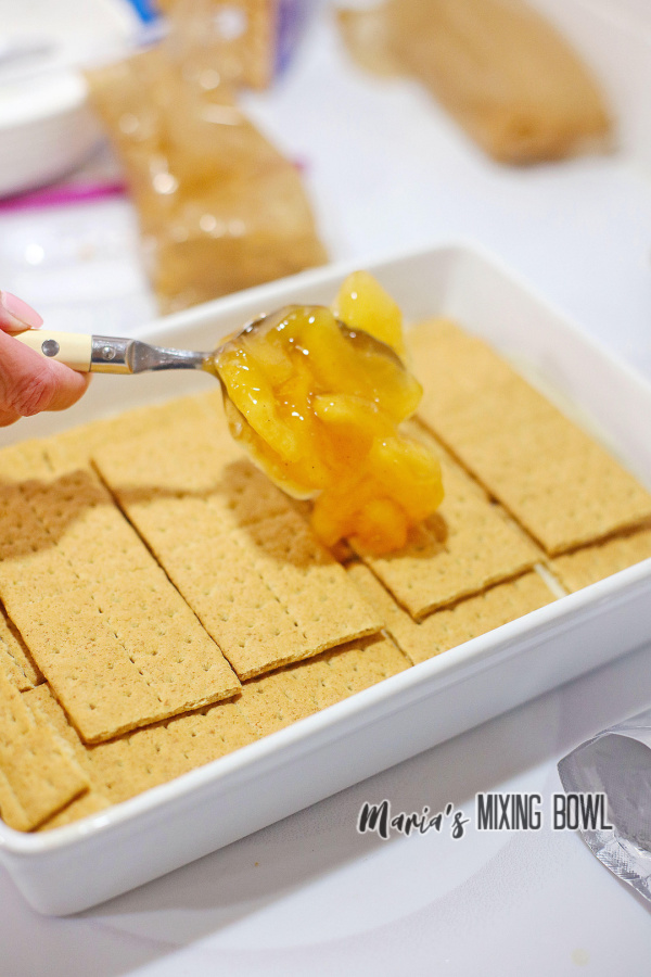 Spooning apple pie filling over graham crackers