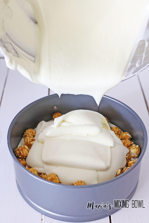 Pouring second layer of cheesecake into springform pan