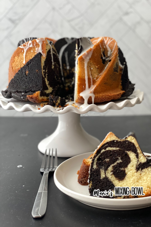 Chocolate vanilla bundt cake on white plate with more cake on white cake stand in background