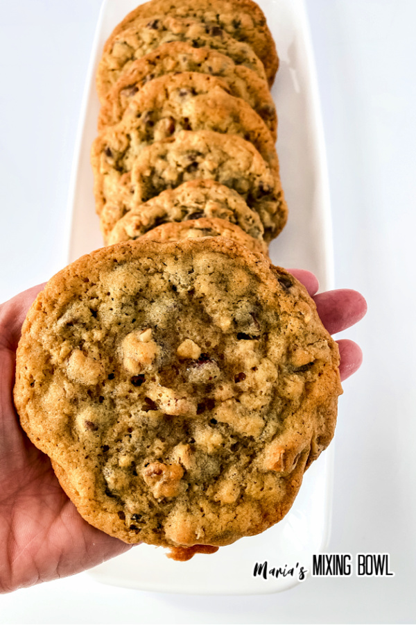 Hand holding cookie above platter with more copycat doubletree chocolate chip cookies