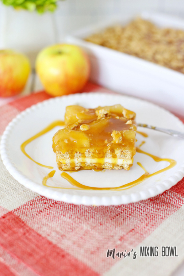 Slice of caramel apple icebox cake on white plate with icebox cake in baking dish in background