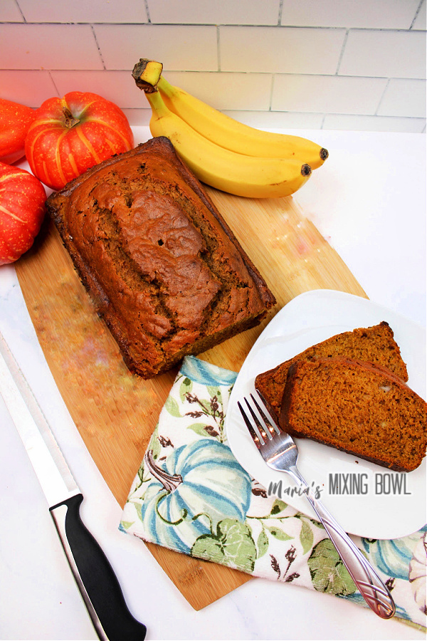 Overhead shot of pumpkin spice banana bread loaf next to slices of banana bread on white plate