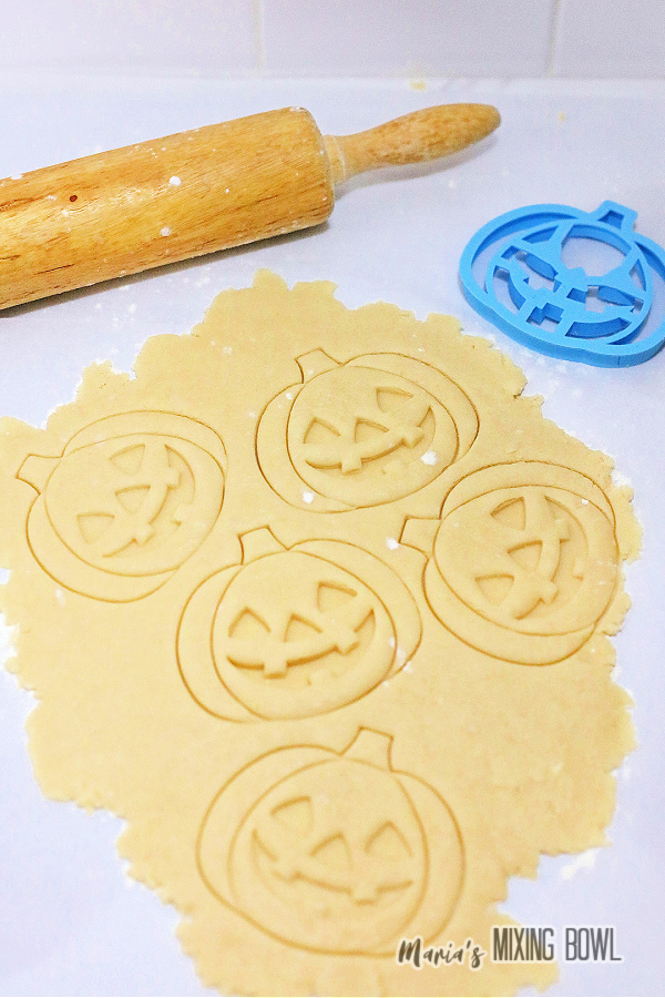 Cookie dough rolled out with pumpkin shapes cut into it