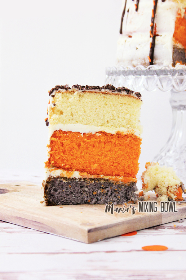 Slice of pumpkin spice latte cake with more cake on cake stand in background