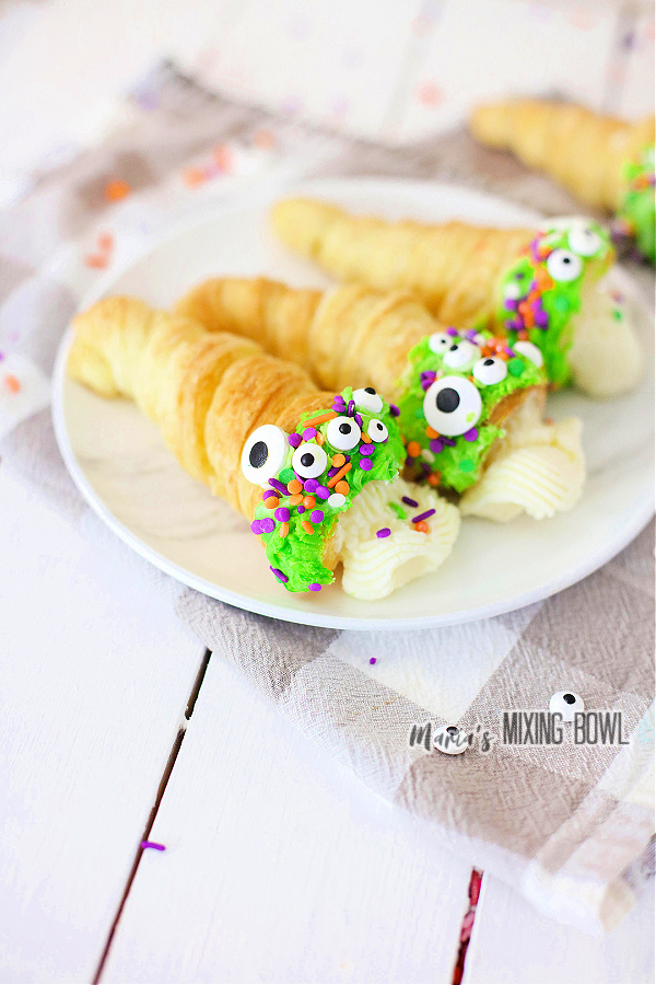 Three Halloween horns filled with cream and decorated with frosting on plate