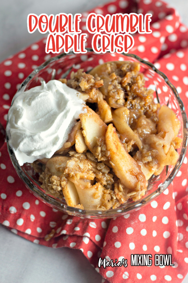 Overhead shot of double crumble apple crisp with whipped cream in glass bowl