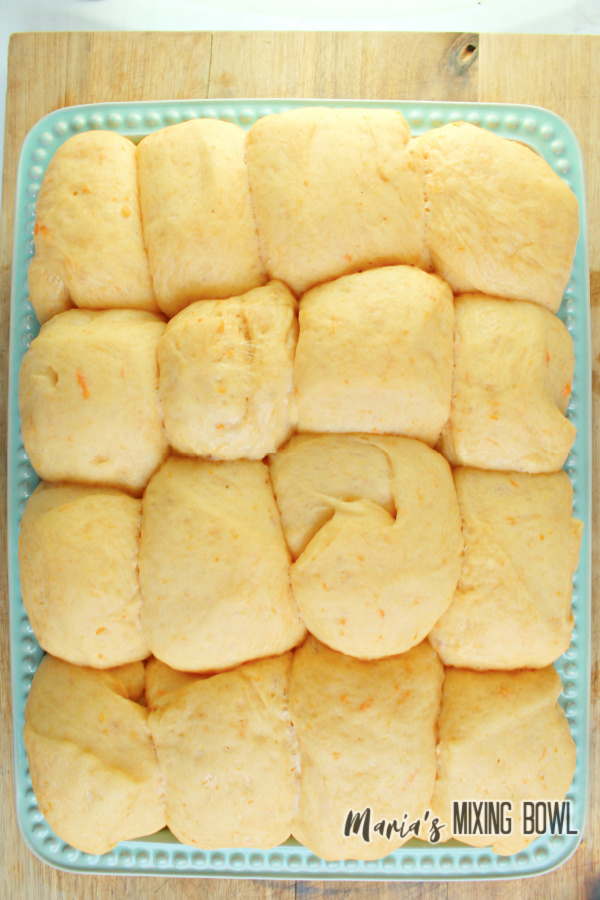 Overhead shot of sweet potato dinner rolls on green serving plate