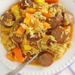 sweet and sour crockpot kielbasa in a white bowl on a blue and white check cloth