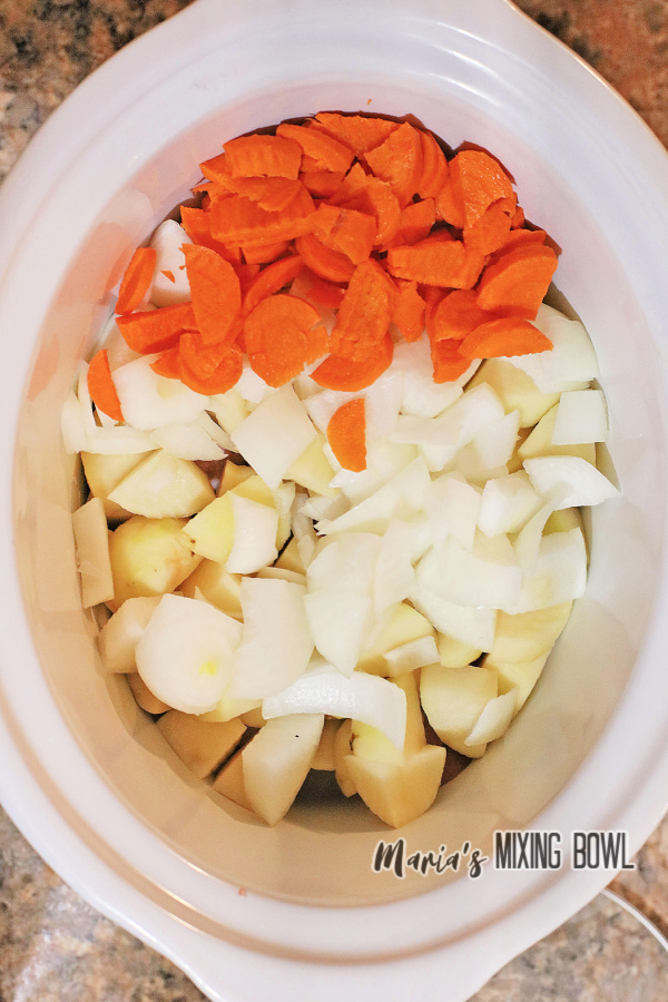 Overhead shot of potatoes, carrots, and onions in slow cooker