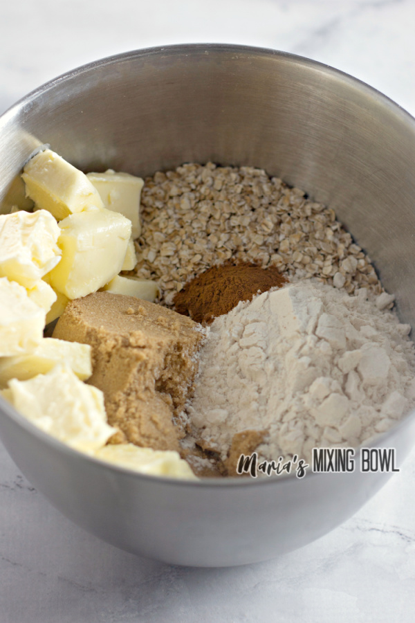 Mixing bowl filled with oats, flour, cinnamon, brown sugar, and butter