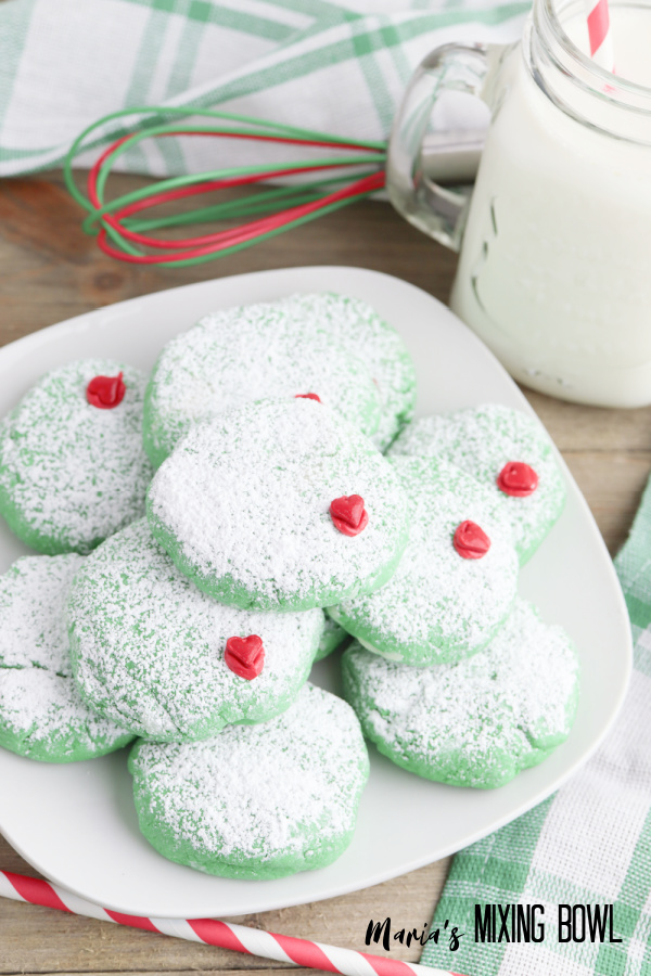 Grinch cookies on white plate next to glass of milk