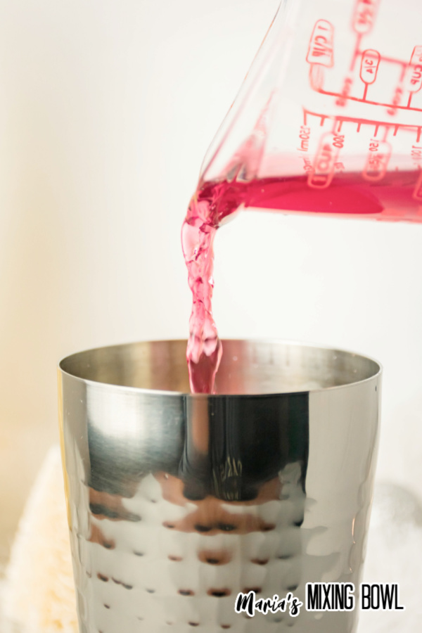 Measuring cup pouring juice into shaker